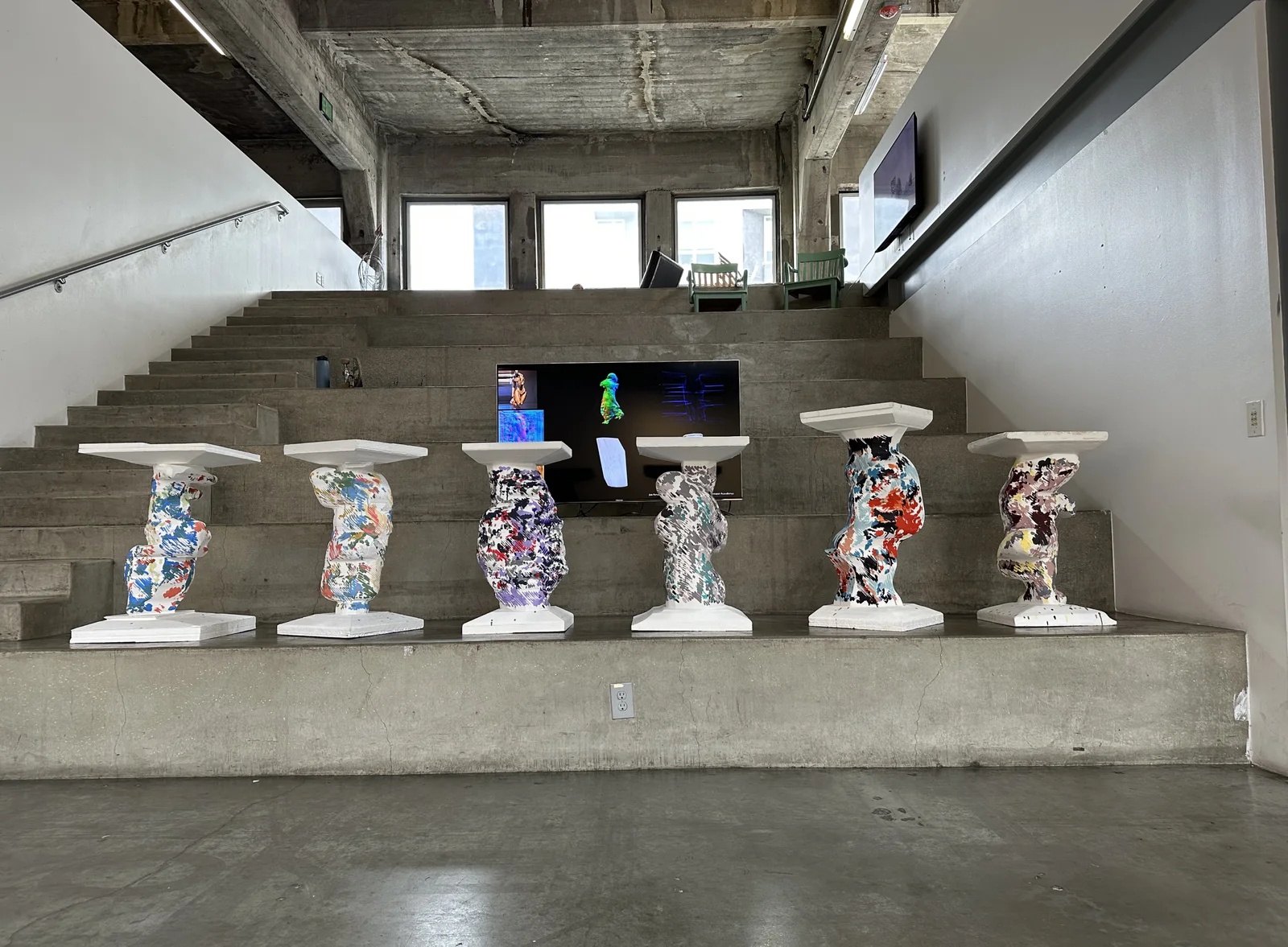 Six painted foam columns displayed on concrete steps